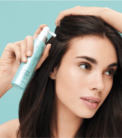 Woman applying ageLOC Scalp & Hair Serum to side of her scalp.