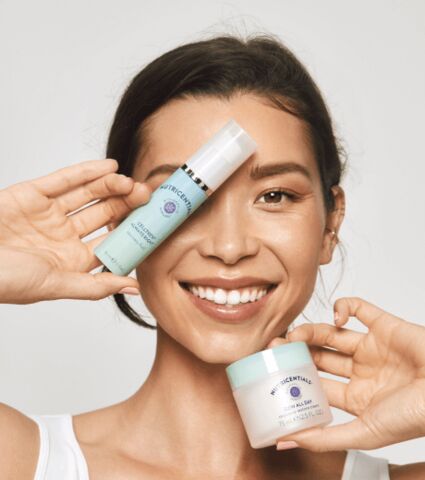 Smiling woman holding Nutricentials products up over her face.