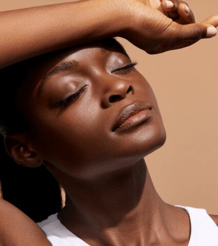Woman with closed eyes holding forearm over forehead.