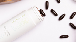 Pharmanex ageLOC Youth on a white table next to its pills. 