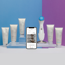 ageLOC Lumispa io device standing next to its cleansers collection and a phone logged into the Vera app. 