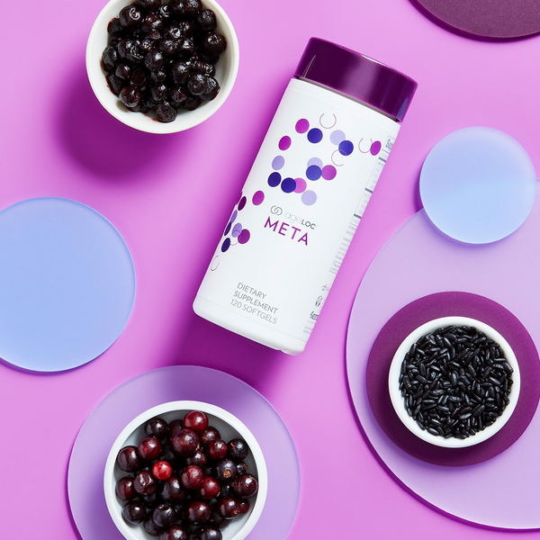 ageLOC Meta bottle lying on a purple-themed display surrounded by various ingredients.