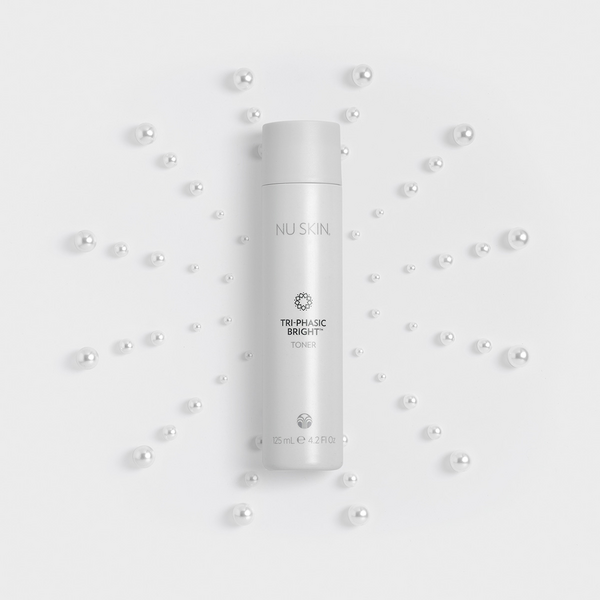 Tri-Phasic Bright Cleanser tube lying over a star pattern of pearls.